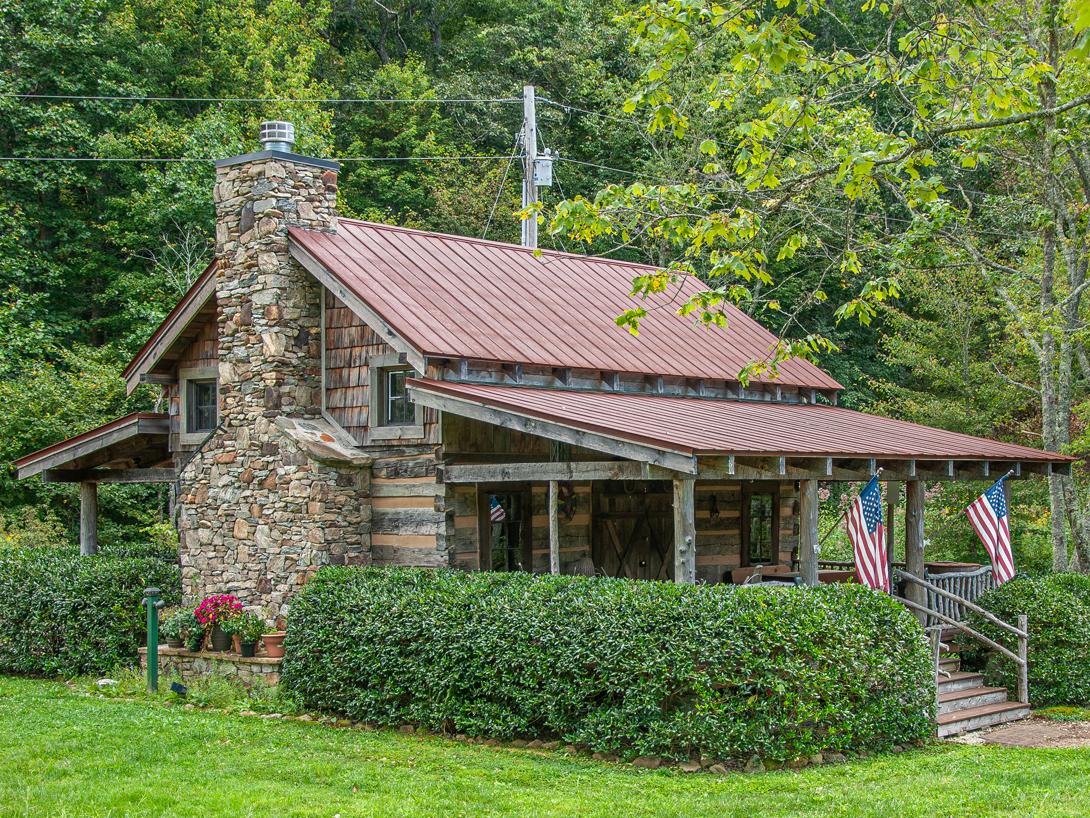 a log cabin with a porch and a stone chimney located in wildflower Creek motorcoach resort